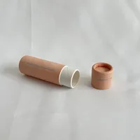 View: Open kraft cardboard lip balm tube lying beside its separate lid, showing the white push-up chamber