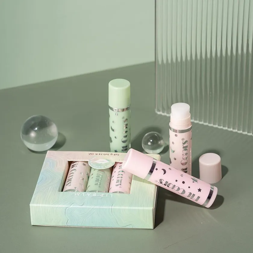Open pastel multipack tray holding four printed lip balm tubes with a lid beside it