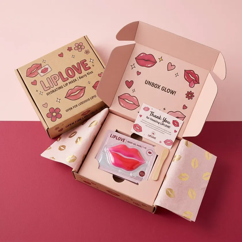 Open pink mailer box containing a lip mask sachet, printed tissue paper and a thank you card