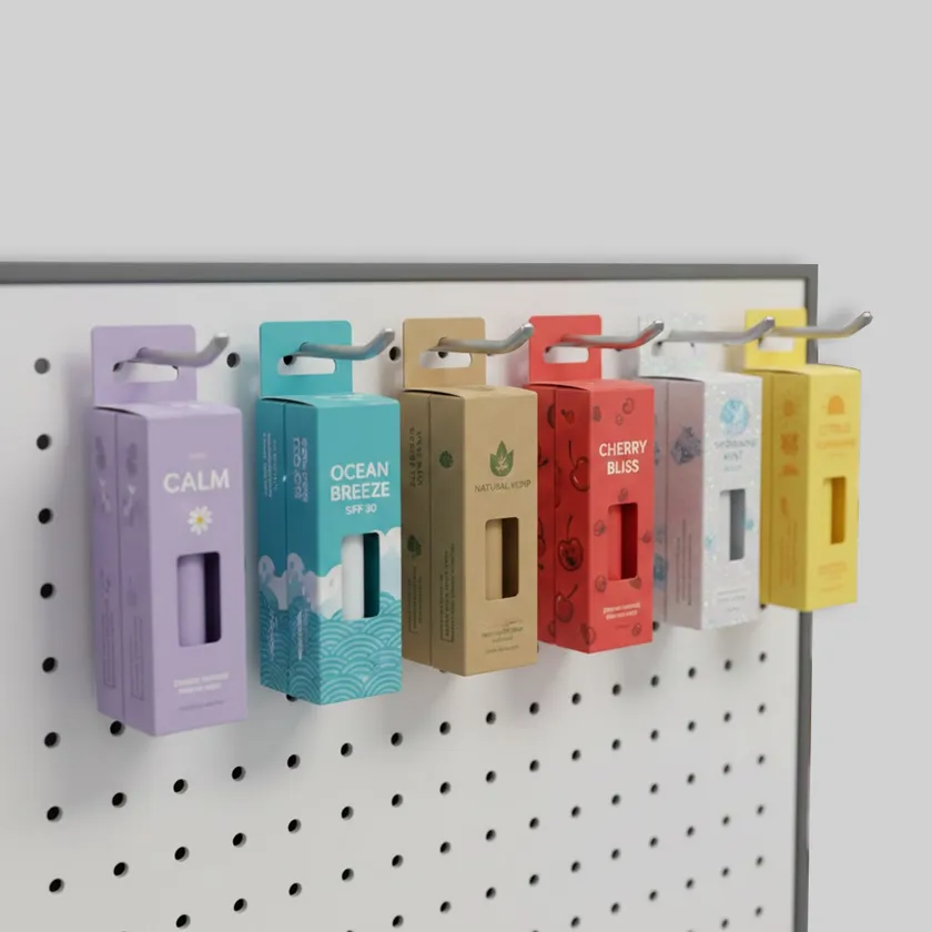 Six coloured hang tab lip balm boxes hanging in a row from hooks on a white pegboard display