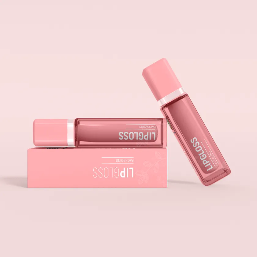Two pale pink lip gloss boxes lying flat with two matching pink gloss tubes beside them
