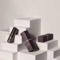 View: Dark plum lipstick cartons arranged on white display blocks with matching lipstick cases