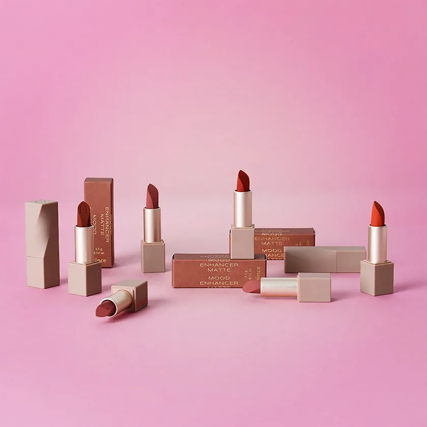 A collection of nude and terracotta lipstick boxes and matching lipstick cases on a pink background