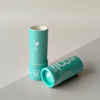 View: Two teal printed paper lip balm tubes lying at an angle, one showing the open push-up chamber